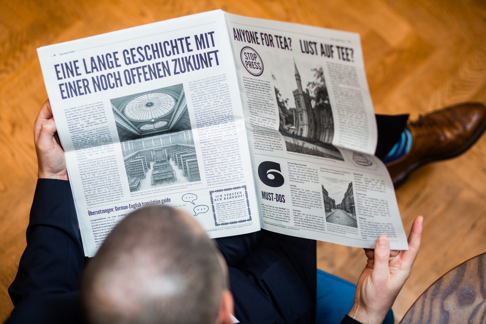 A wedding guest holding up a printed wedding newspaper, reading the front page