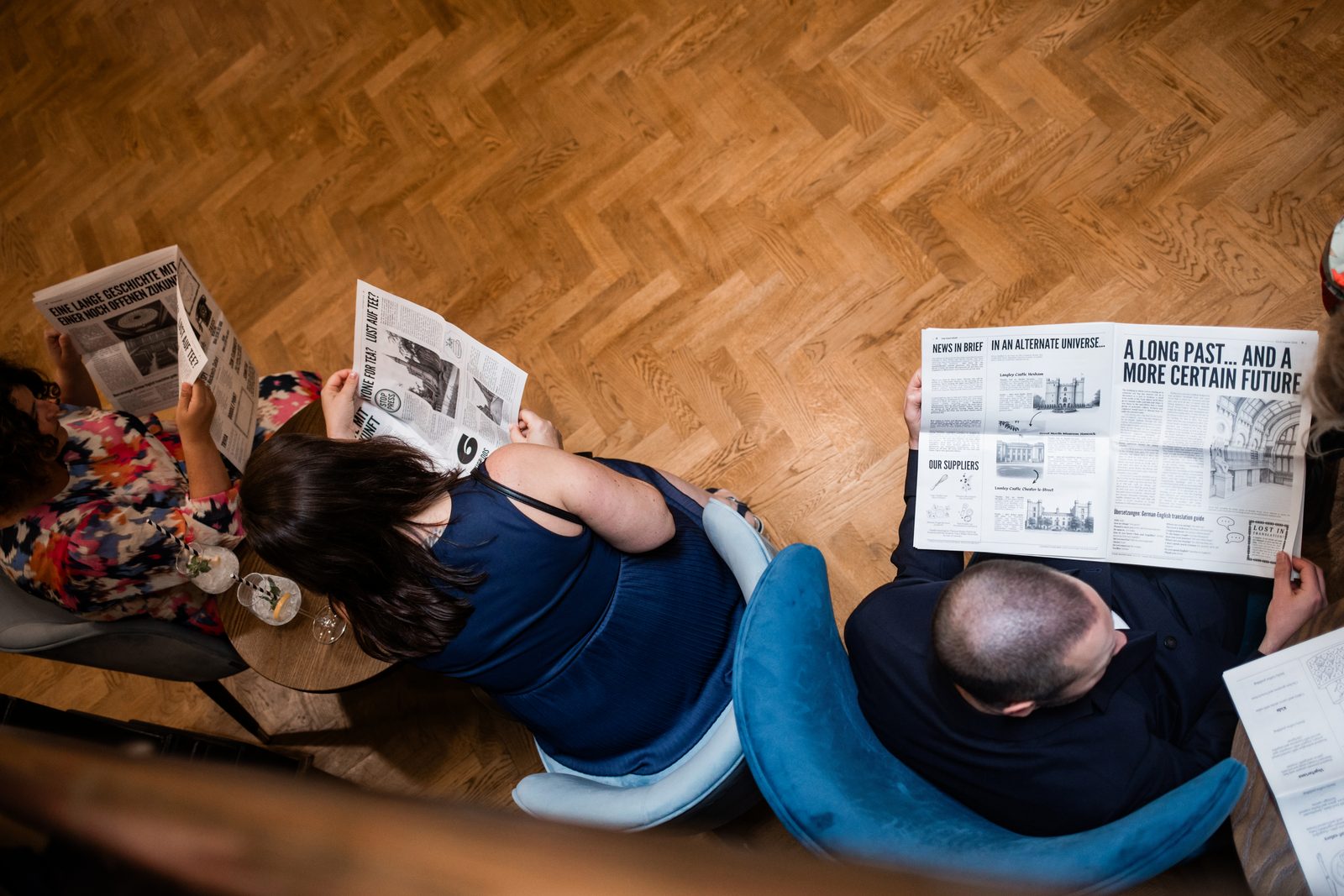 Wedding guests seen from above, sitting in armchairs and reading the newspaper